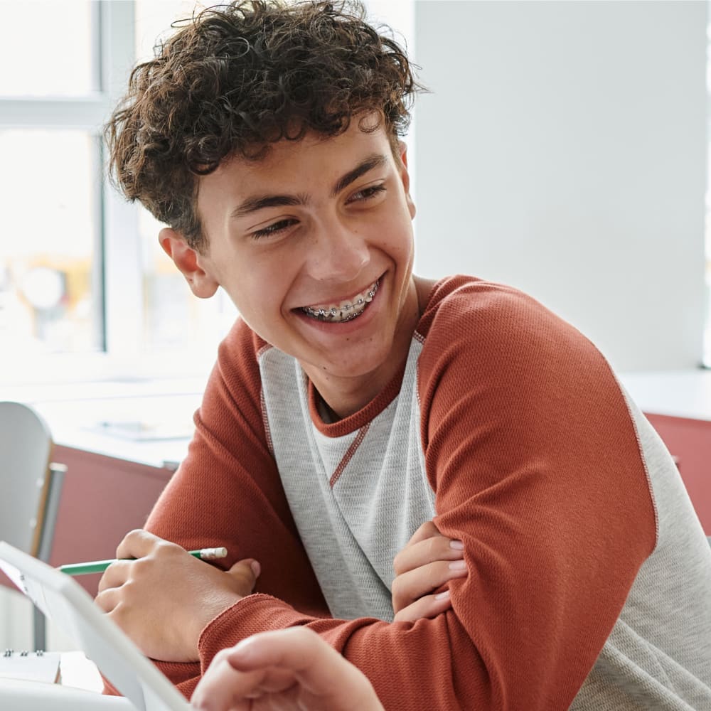 A teenage boy smiles, showing off his braces.