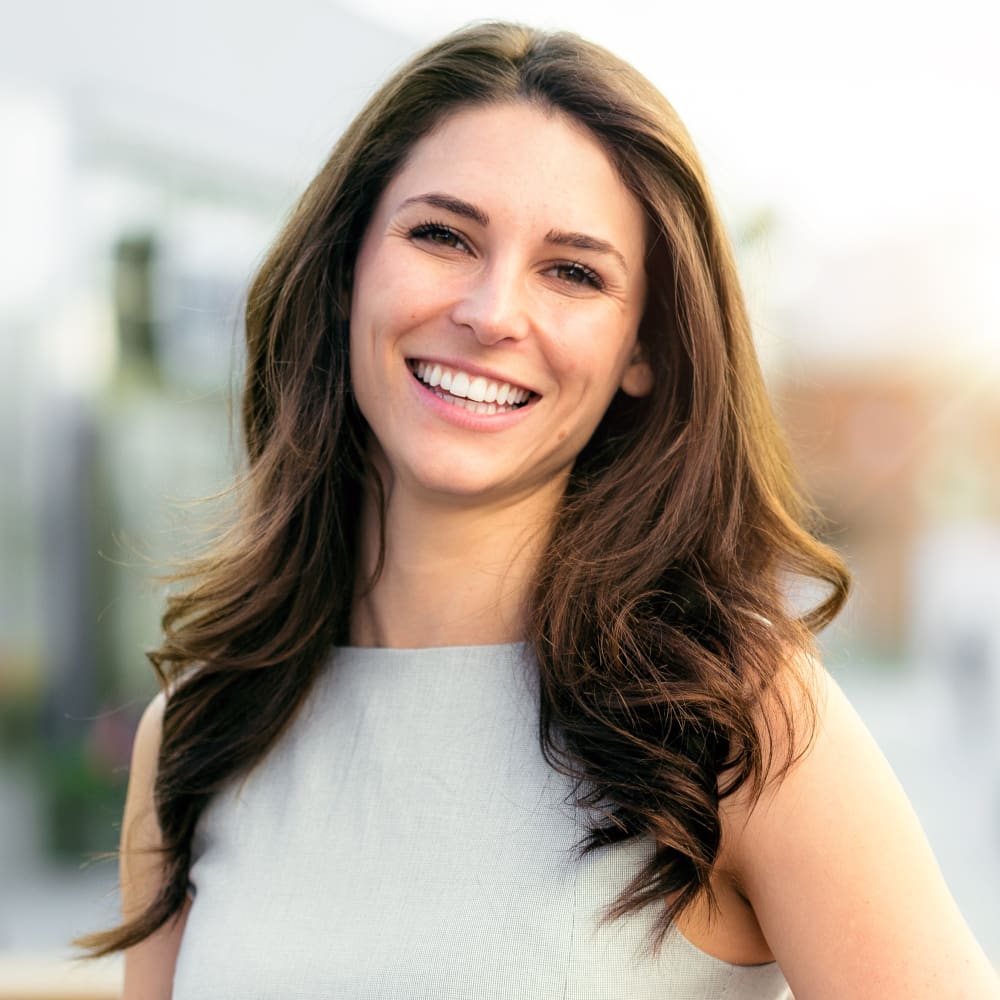 A woman stands outside smiling.
